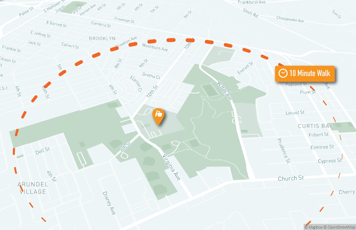Oblique aerial view of a street map of the area around Bay Brook EMS (marked with an orange marker) with the 10 minute walking distance marked in an orange dashed line.